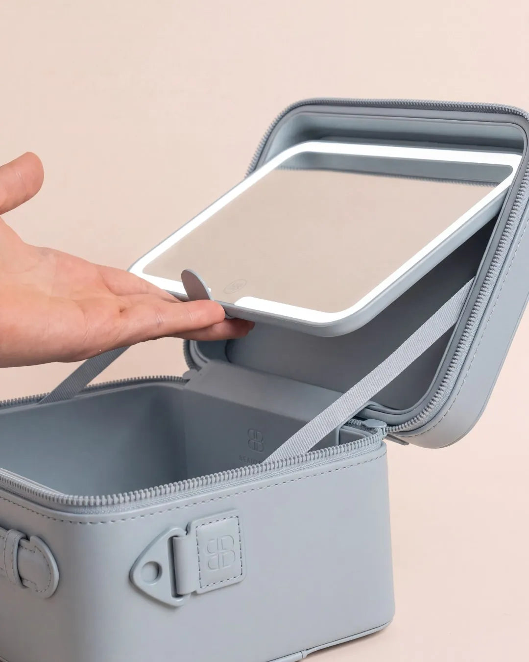 A hand lifts the removable LED mirror out of the open GO mini Powder Blue